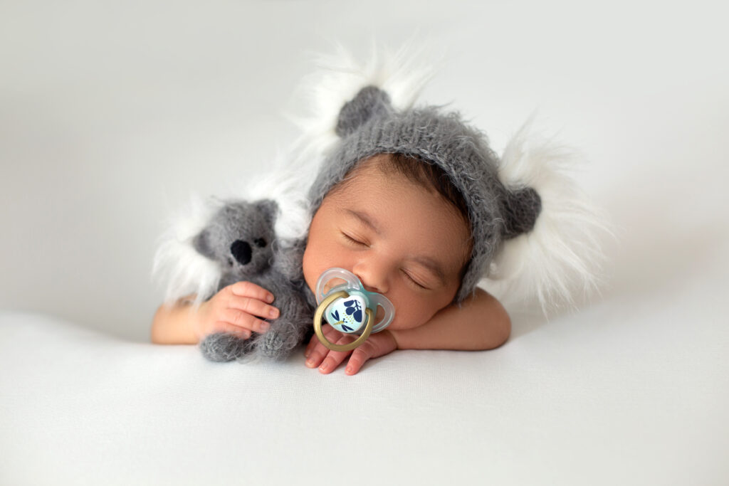 newborn babyboy cute little resting baby with grey hat grey toy bear his hand pacifier his mouth white floor